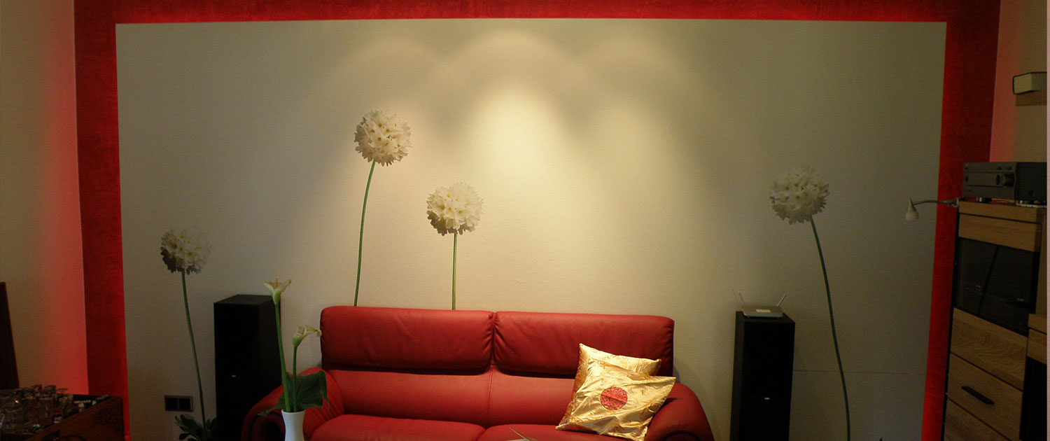 Ein rotes Sofa vor einer mit weißen Blumen tapezierten Wand